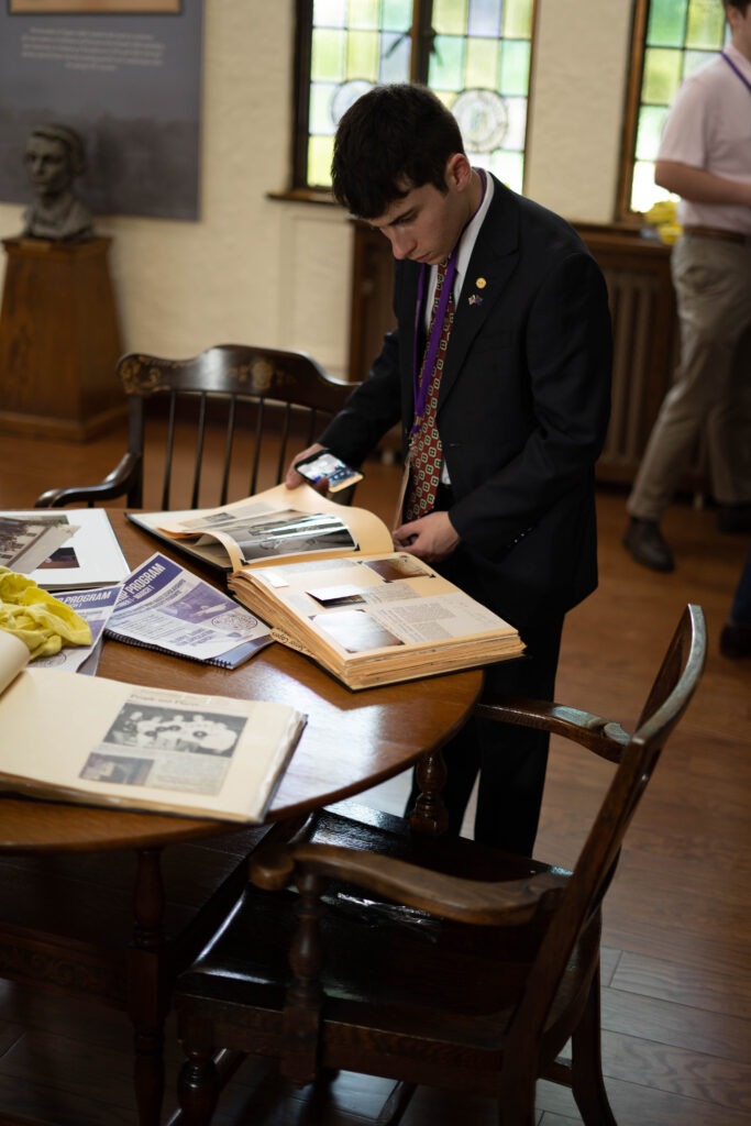 Sigma Alpha Epsilon brother reading a scrapbook in the library
